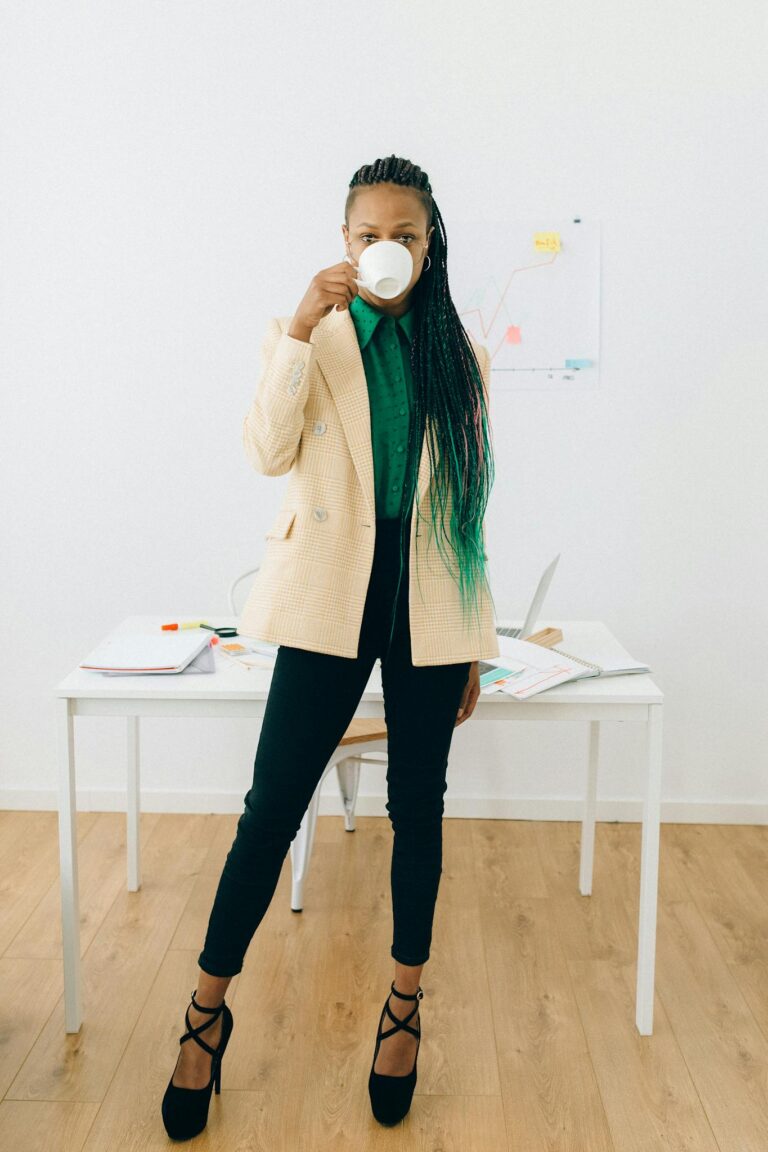 Businesswoman standing with coffee cup in office, focused on reports.